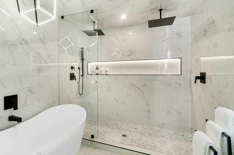 walk in shower with marble tile walls